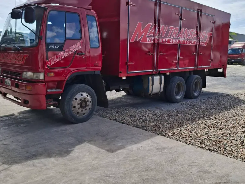 Large red Main Transport Hino ten-wheeler box truck with side-opening cargo doors, at the Suva depot