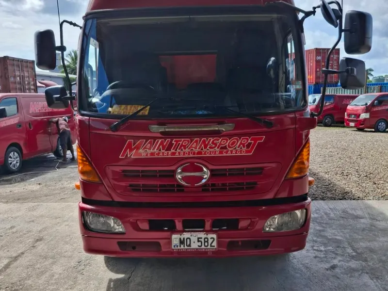 Front view of a red Main Transport Hino truck with the company name across the cab, at the Suva depot